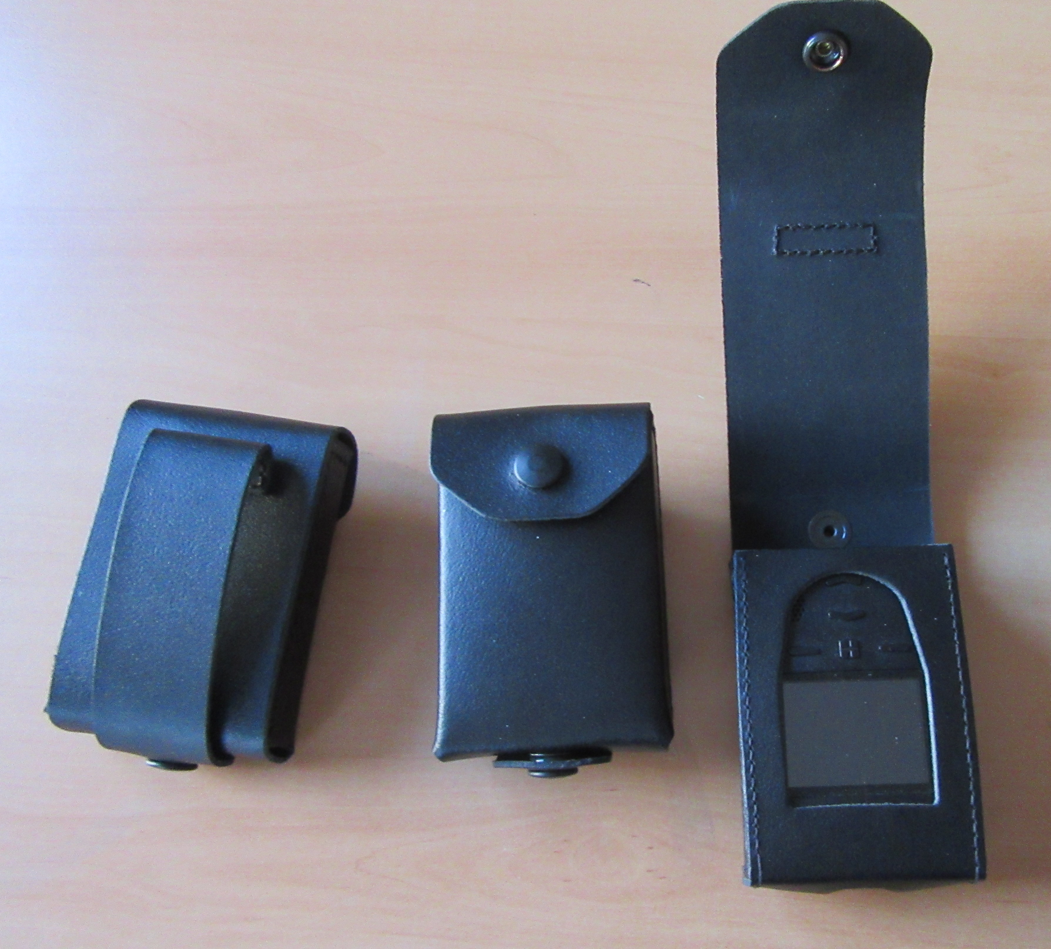 Three black leather cases on a table, two closed, one open with a window.