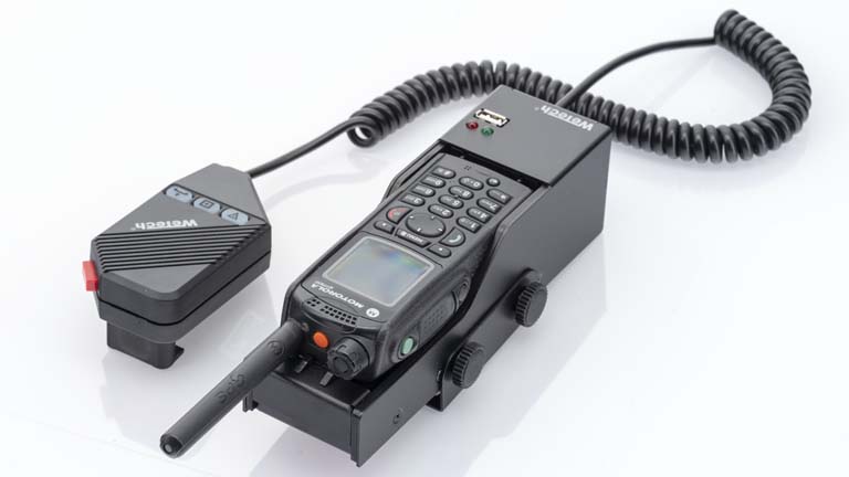 7000-00751492_wem_03.jpg Radio with handset on a charging dock, cable connected