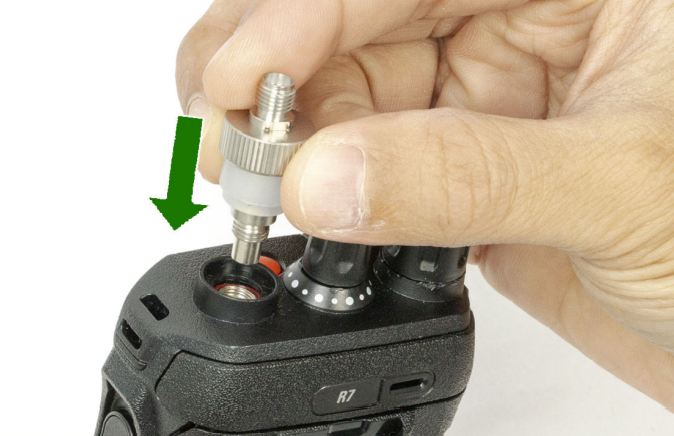 7000-00753410_mot_01.png Hand befestigt Adapter auf Funkgerät mit grünem Pfeil, der zur Buchse zeigt.