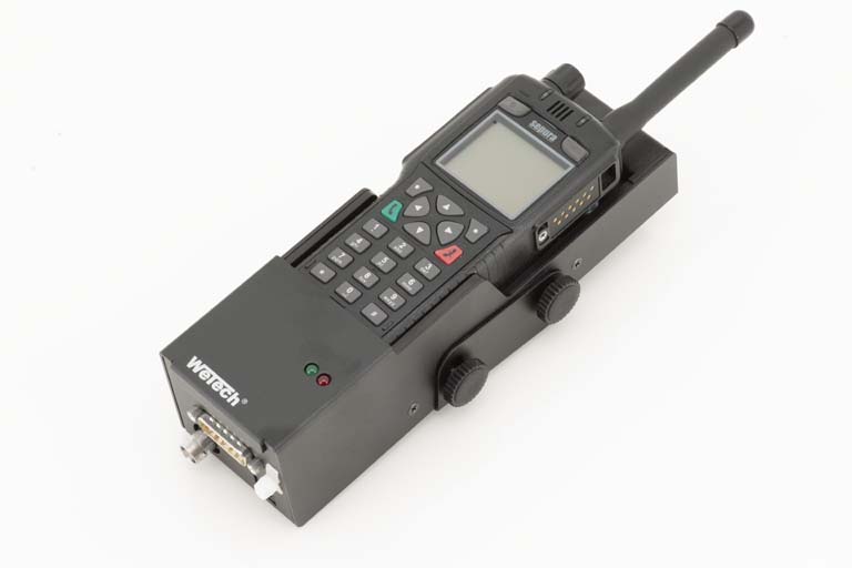 Funkgerät mit Tastenfeld und Antenne, montiert auf schwarzer Halterung.