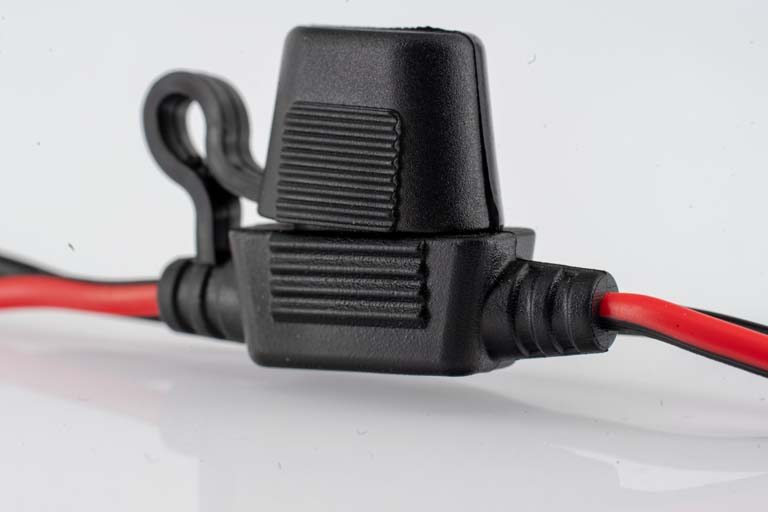 Close-up of a black fuse holder with red wires