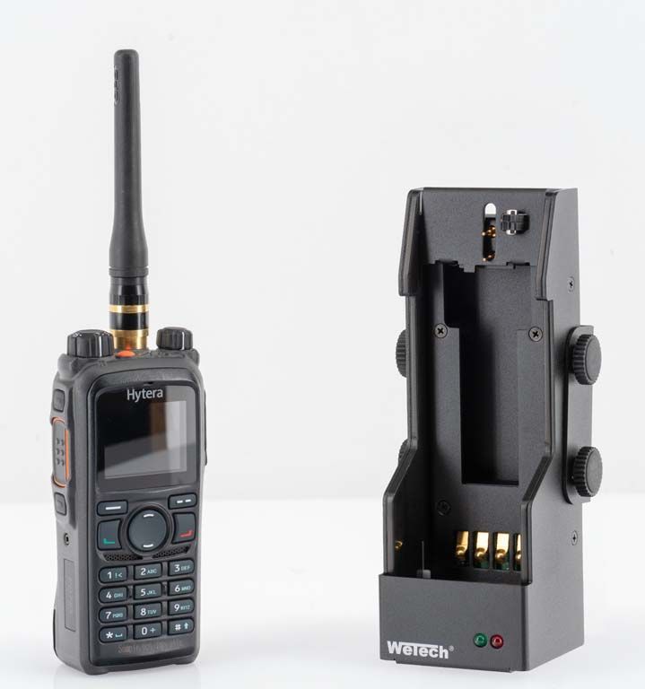 Funkgerät mit Antenne neben leerem Ladegerät.