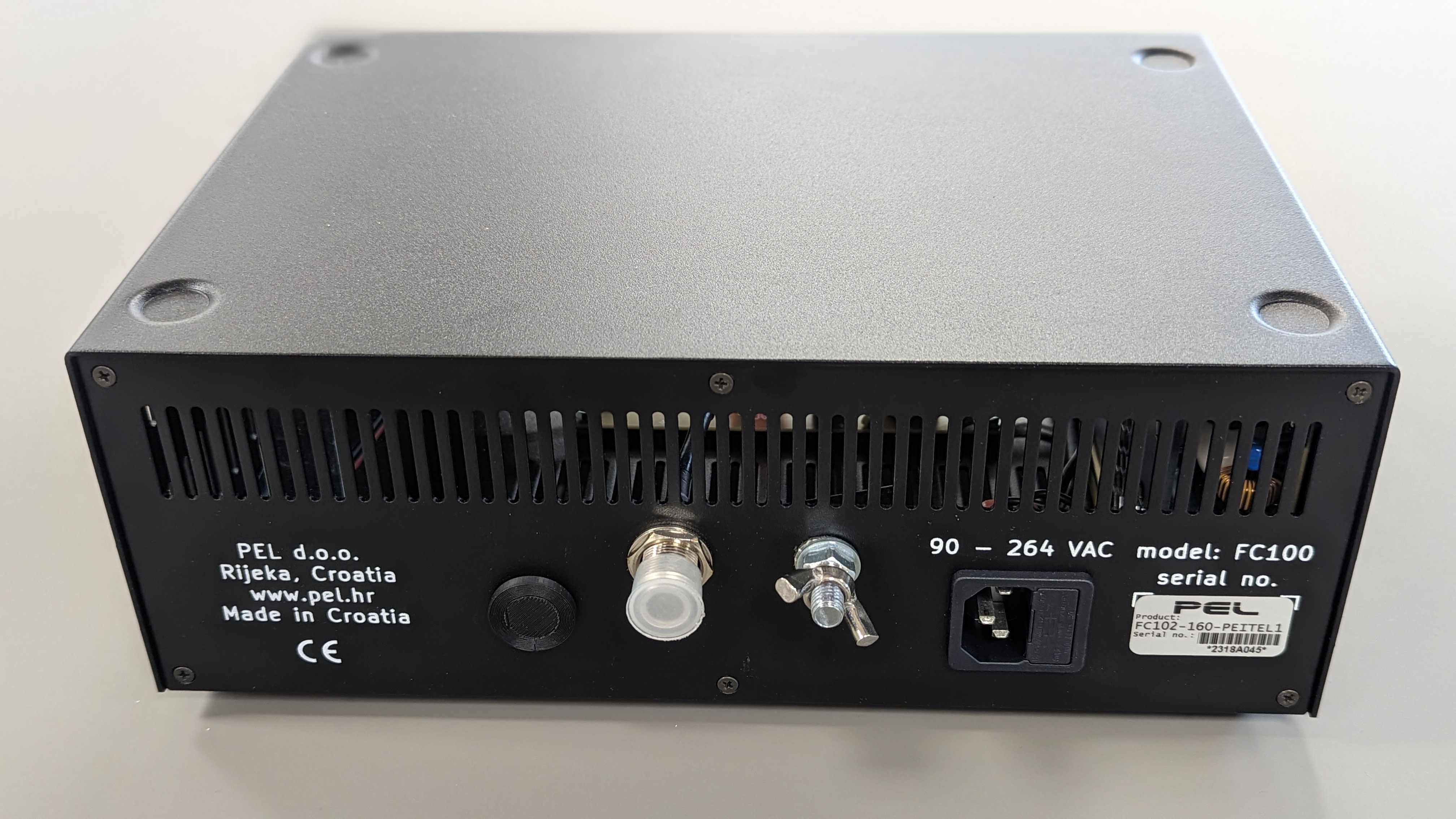 Black electrical device with connectors and serial number sticker.