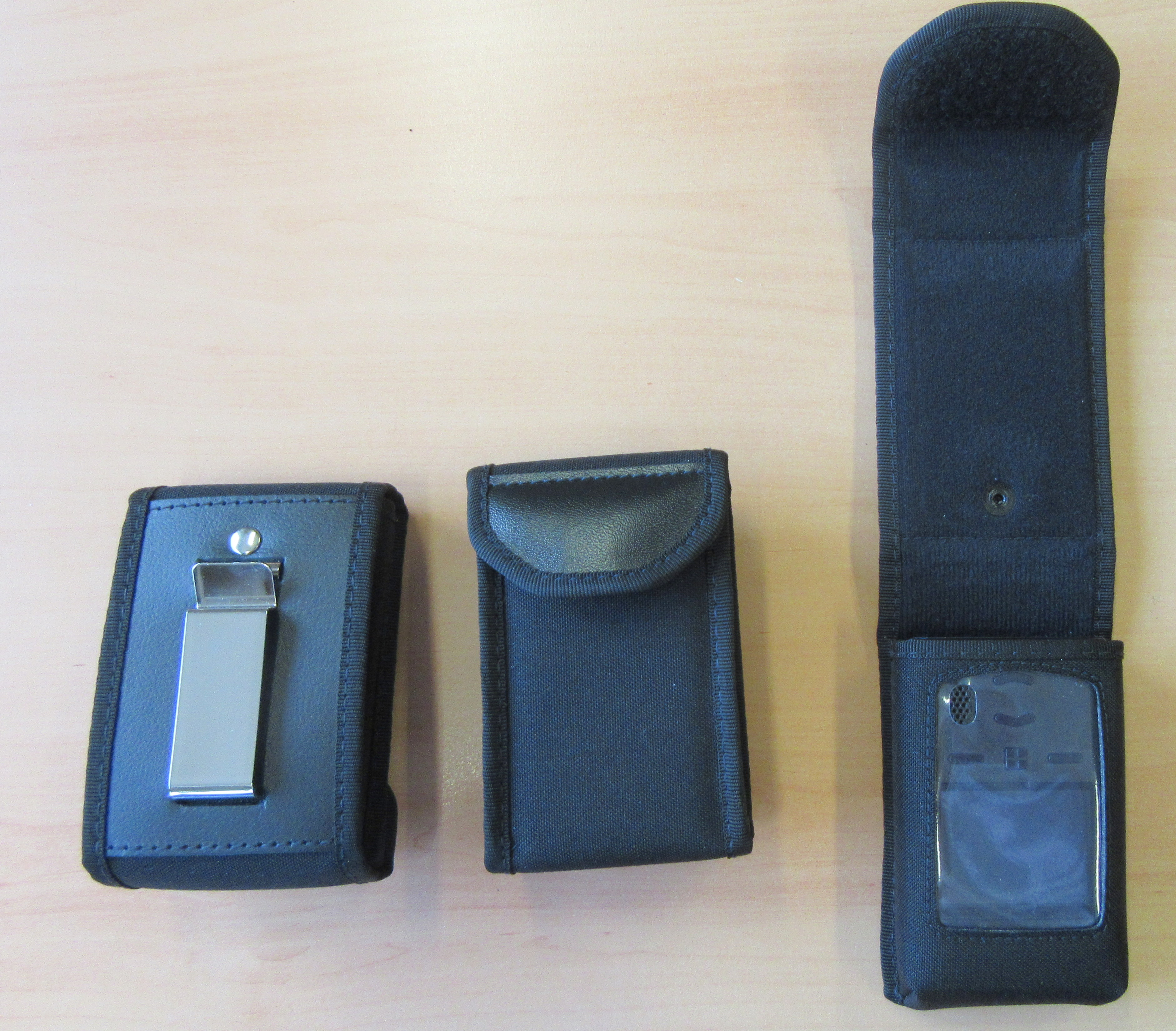 Drei schwarze Etuis aus Stoff auf Holzoberfläche, eines ist offen.