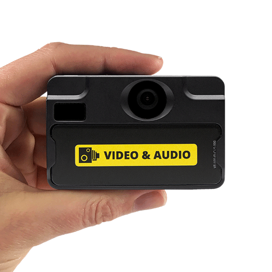 Hand hält schwarze Kamera mit gelbem Video & Audio Aufkleber.