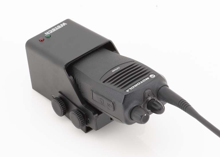 7000-00739400_wem_03zlqpcwy5hee7x.jpg Funkgerät auf Ladestation mit Kabelanschluss und Bedienknöpfen.