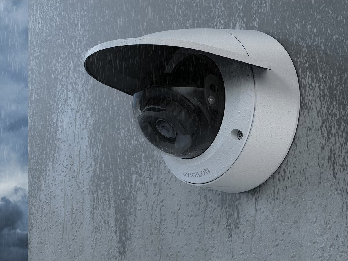 Surveillance camera mounted on a wall in the rain.