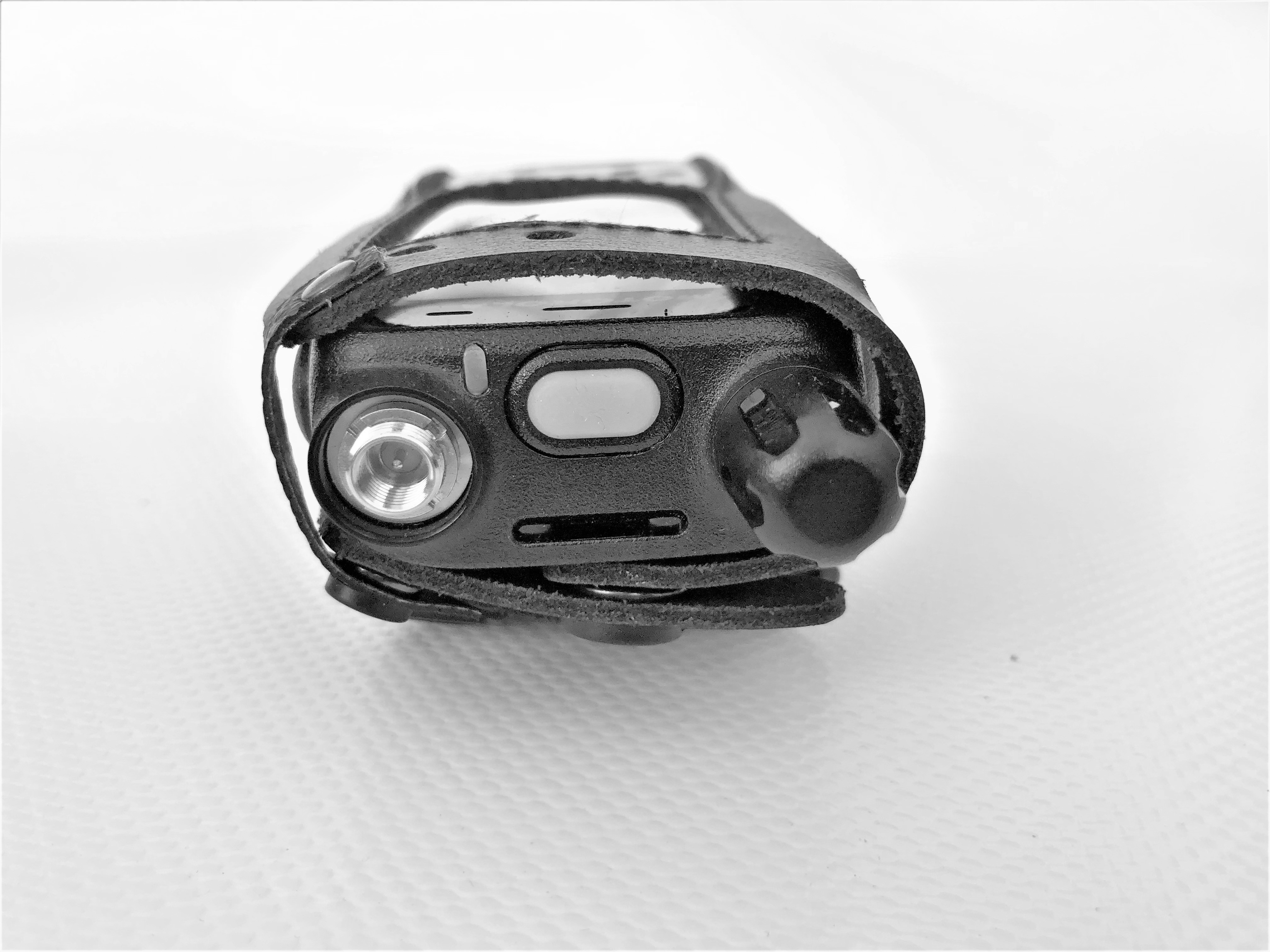 Handheld radio in a leather case on a white surface.