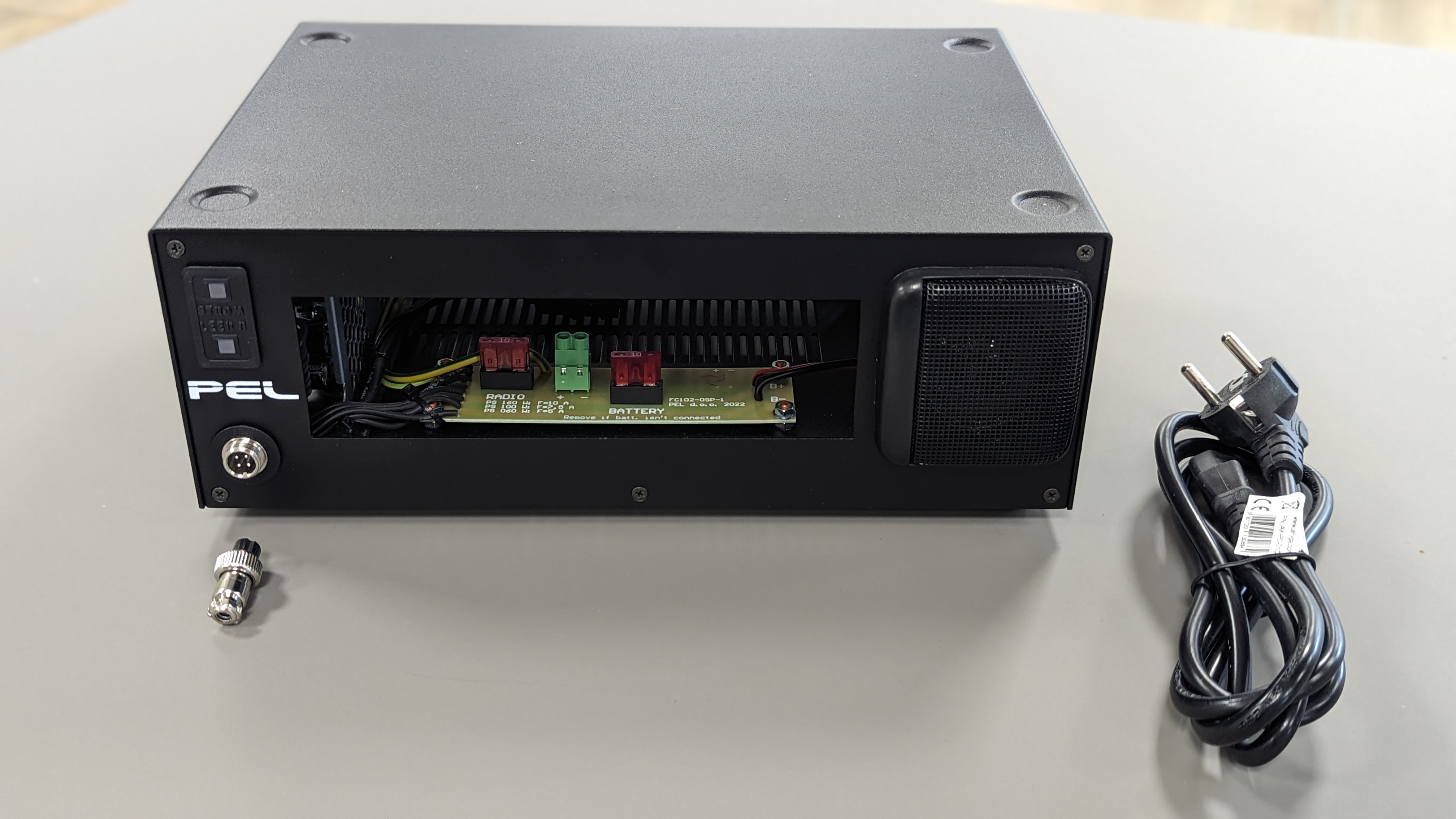 Black box with open front showing wiring, connector and power cable beside.