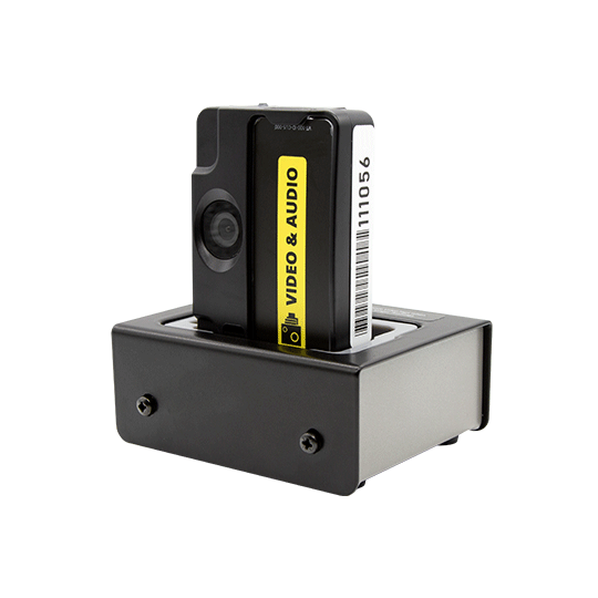 Small black camera in docking station with yellow video and audio label.