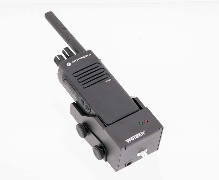 Black walkie-talkie with antenna and two knobs on charging station.