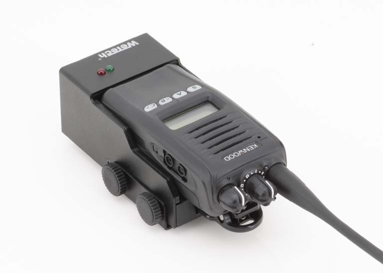 Tragbares Funkgerät mit Display und Kabel, montiert auf einer Halterung.