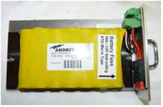 Gelbe Batterie mit Sicherung, Kabeln und Stecker an einem Metallrahmen montiert.