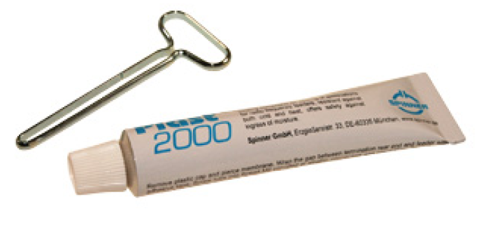 Metallschlüssel und Tube mit blauer Aufschrift 'Plast 2000'.