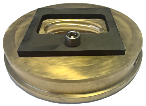 Round metal plate with rectangular recessed insert and central screw.